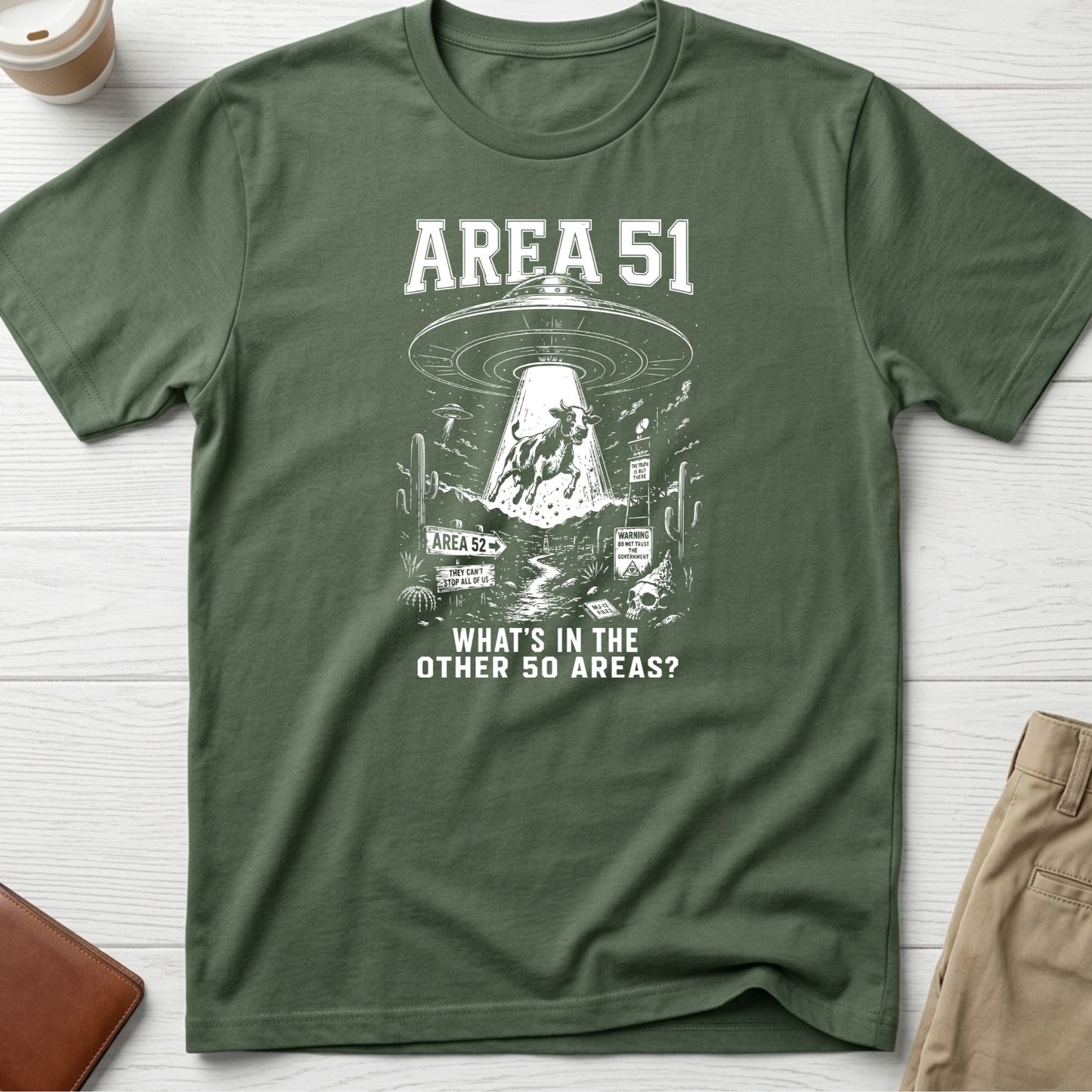 Area 51 graphic t-shirt featuring a flying saucer abducting a cow with the funny quote "What's In The Other 50 Areas?" on a green unisex tee.