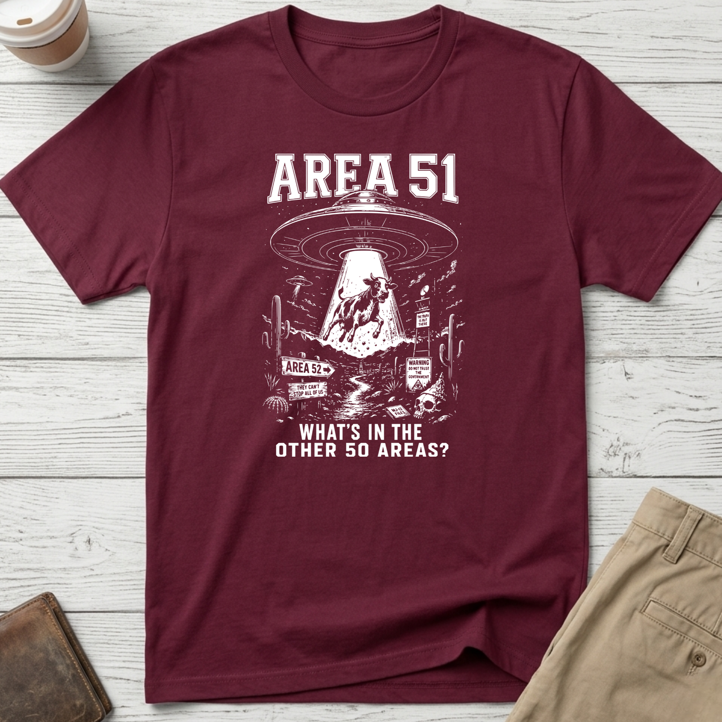 Area 51 graphic t-shirt featuring a flying saucer abducting a cow with the funny quote "What's In The Other 50 Areas?" on a maroon unisex tee.