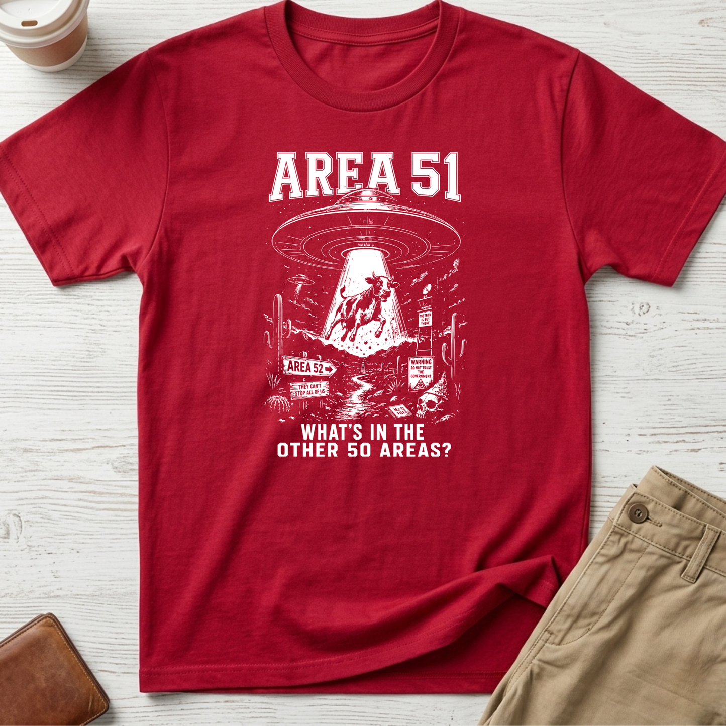 Area 51 graphic t-shirt featuring a flying saucer abducting a cow with the funny quote "What's In The Other 50 Areas?" on a red unisex tee.