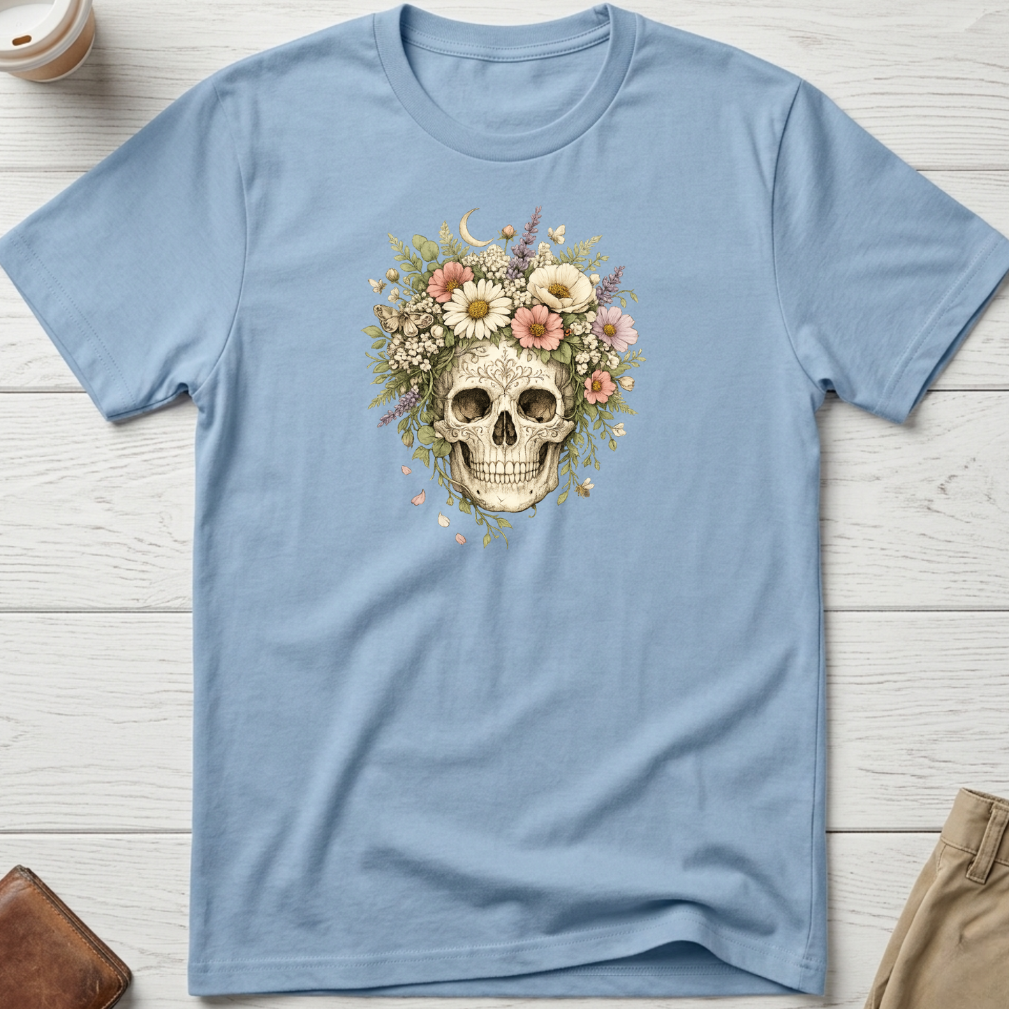 Floral Skull graphic t-shirt featuring a vintage skull surrounded by blooming wildflowers and botanical elements on a blue unisex tee.