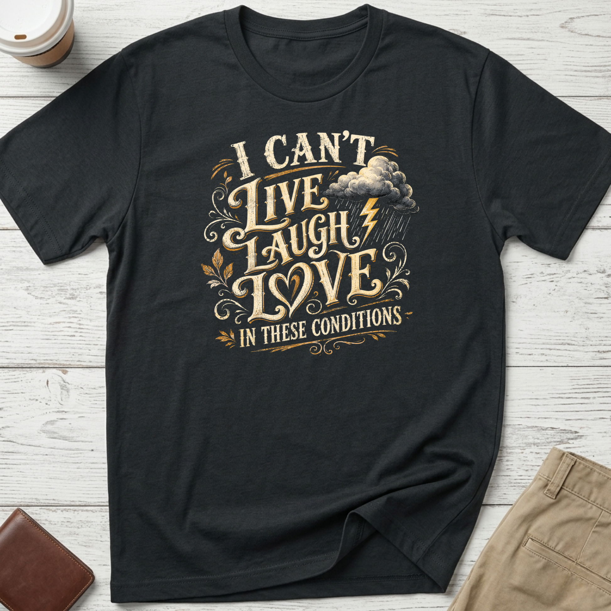 I Can’t Live Laugh Love In These Conditions funny sarcastic t-shirt featuring vintage cream lettering with storm cloud and lightning graphic on a black unisex tee.