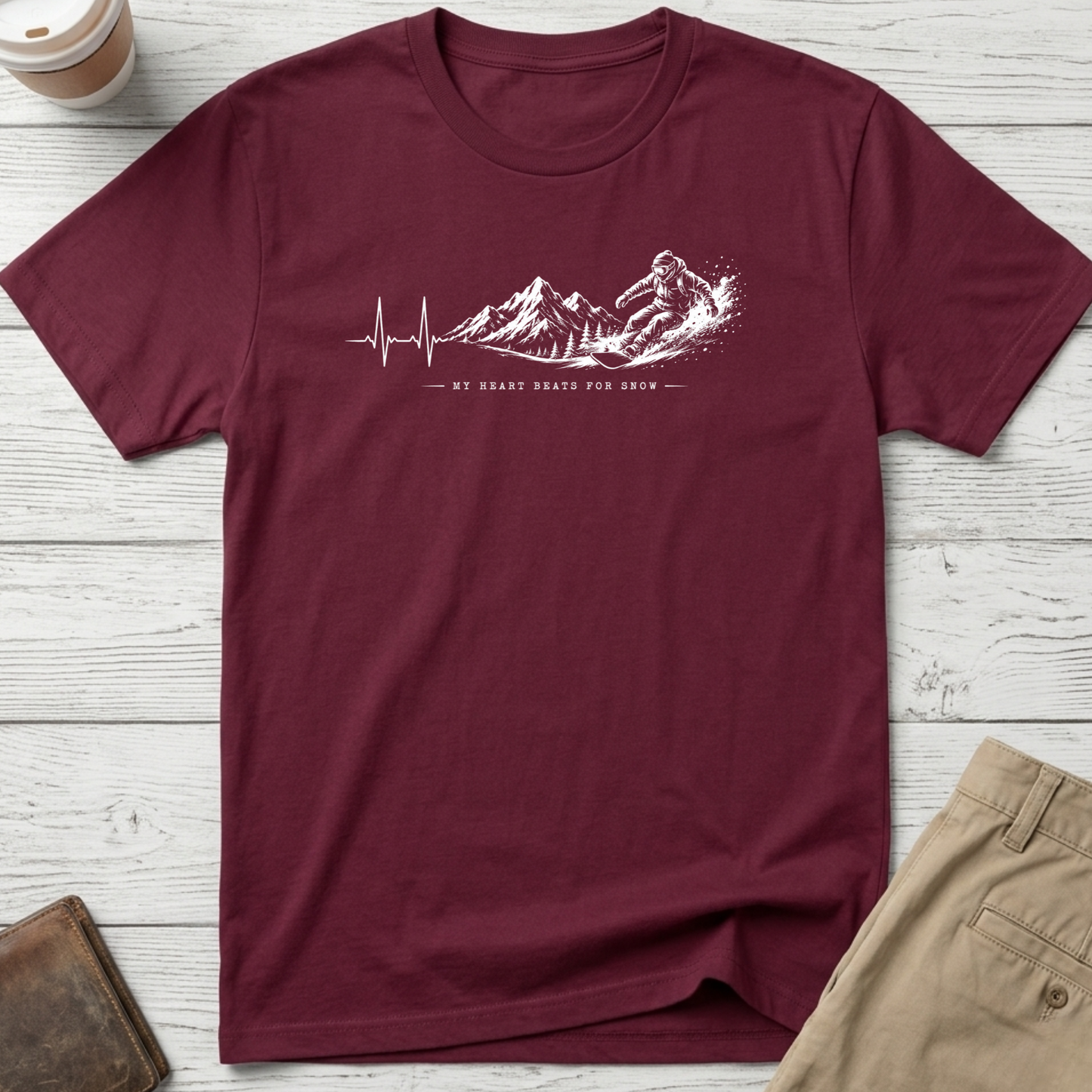 My Heart Beats for Snow graphic t-shirt featuring an ECG heartbeat transforming into mountain peaks with a snowboarder on a maroon unisex tee.