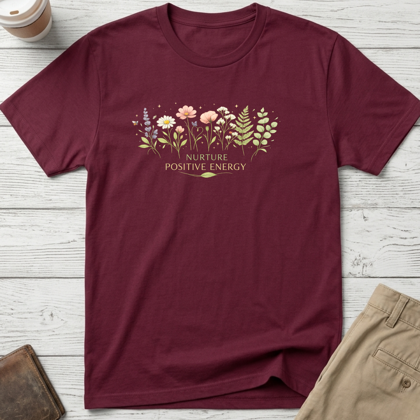Nurture Positive Energy graphic t-shirt featuring elegant botanical wildflowers and inspirational typography on a maroon unisex tee.