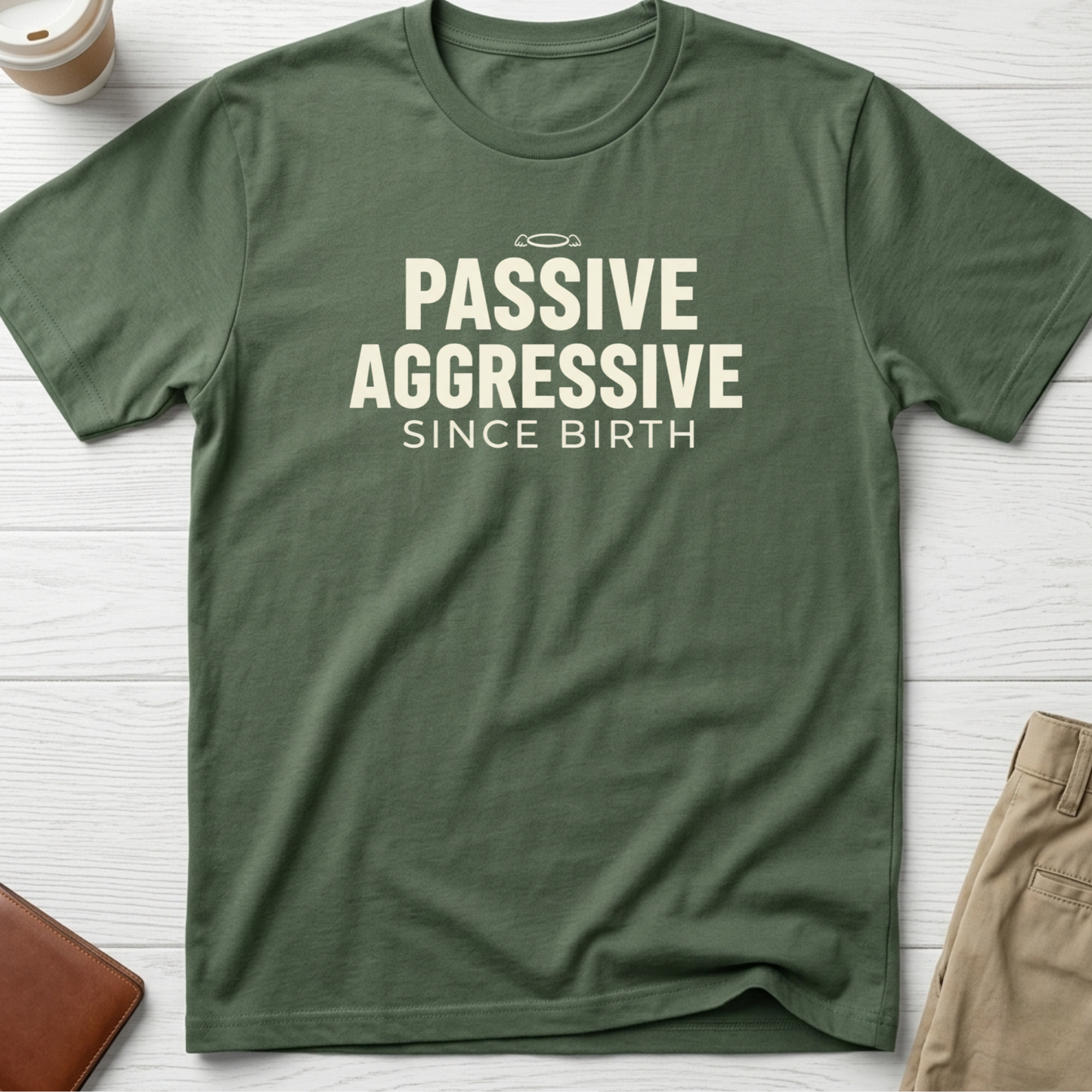 Passive Aggressive Since Birth funny sarcastic t-shirt featuring bold cream text and small halo graphic on a green unisex tee.
