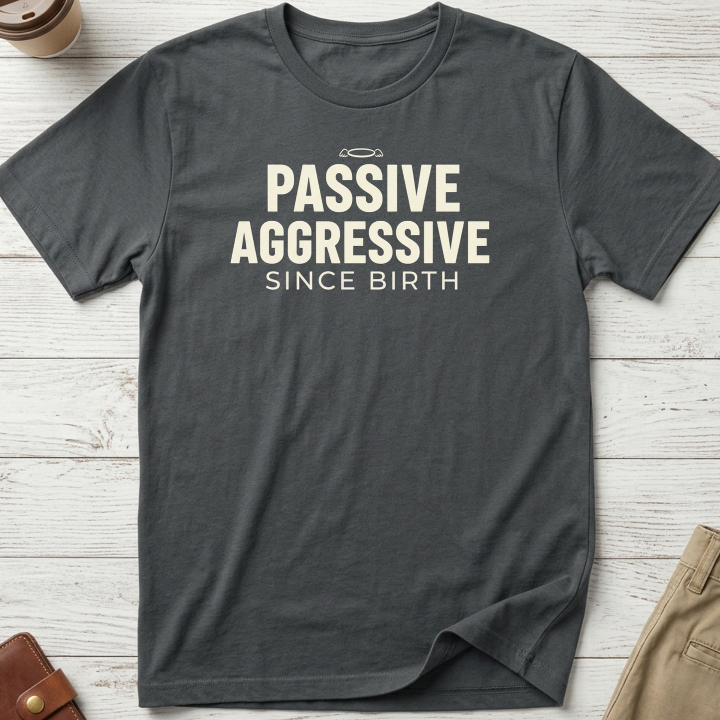 Passive Aggressive Since Birth funny sarcastic t-shirt featuring bold cream text and small halo graphic on a grey unisex tee.