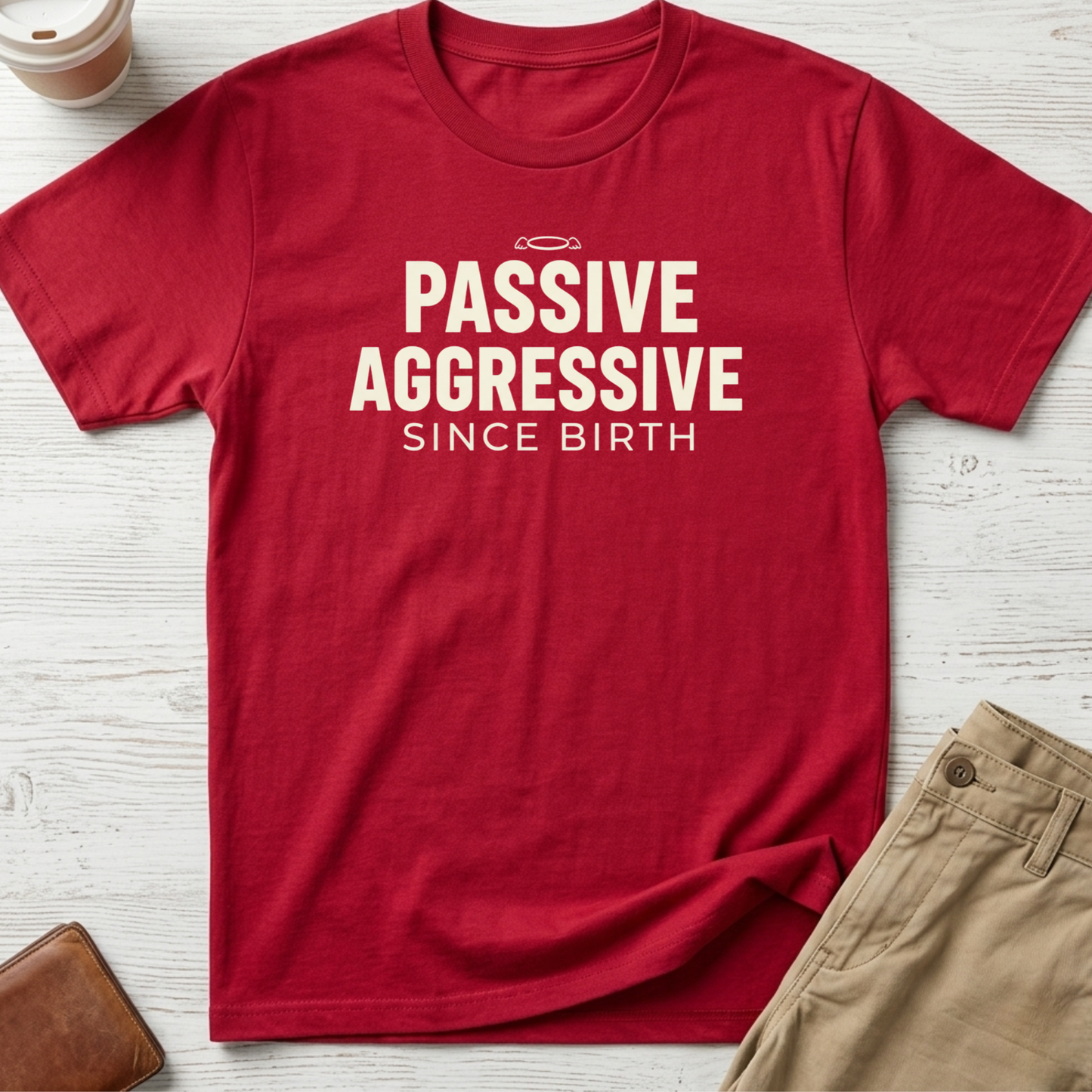 Passive Aggressive Since Birth funny sarcastic t-shirt featuring bold cream text and small halo graphic on a red unisex tee.