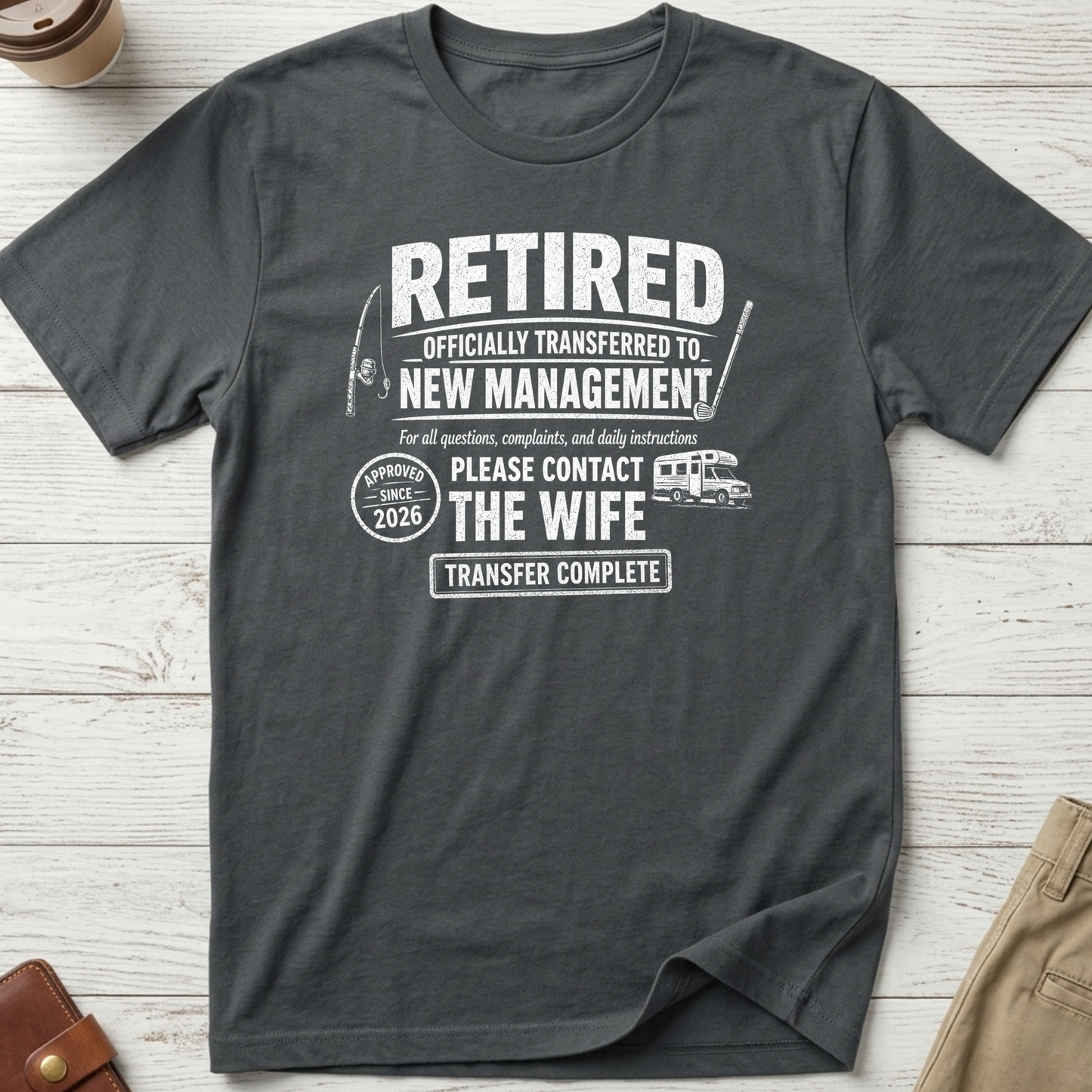 Retired Officially Transferred to New Management graphic t-shirt featuring funny retirement quote with golf clubs, campervan and wife joke on charcoal unisex tee.