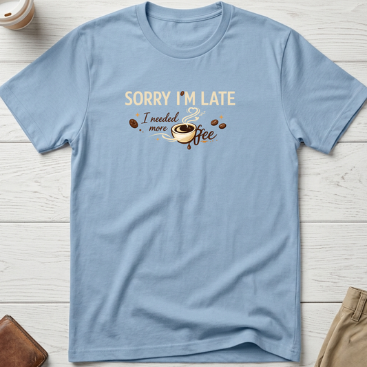Sorry I'm Late I Needed More Coffee graphic t-shirt featuring playful coffee quote and steaming coffee cup illustration on blue unisex tee.