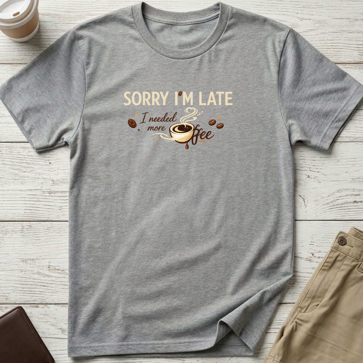 Sorry I'm Late I Needed More Coffee graphic t-shirt featuring playful coffee quote and steaming coffee cup illustration on light grey unisex tee.
