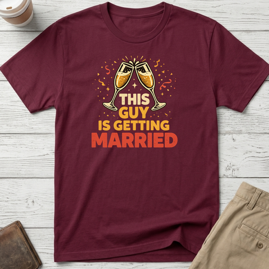This Guy Is Getting Married graphic t-shirt featuring champagne glasses and bold celebration typography on a maroon unisex tee.