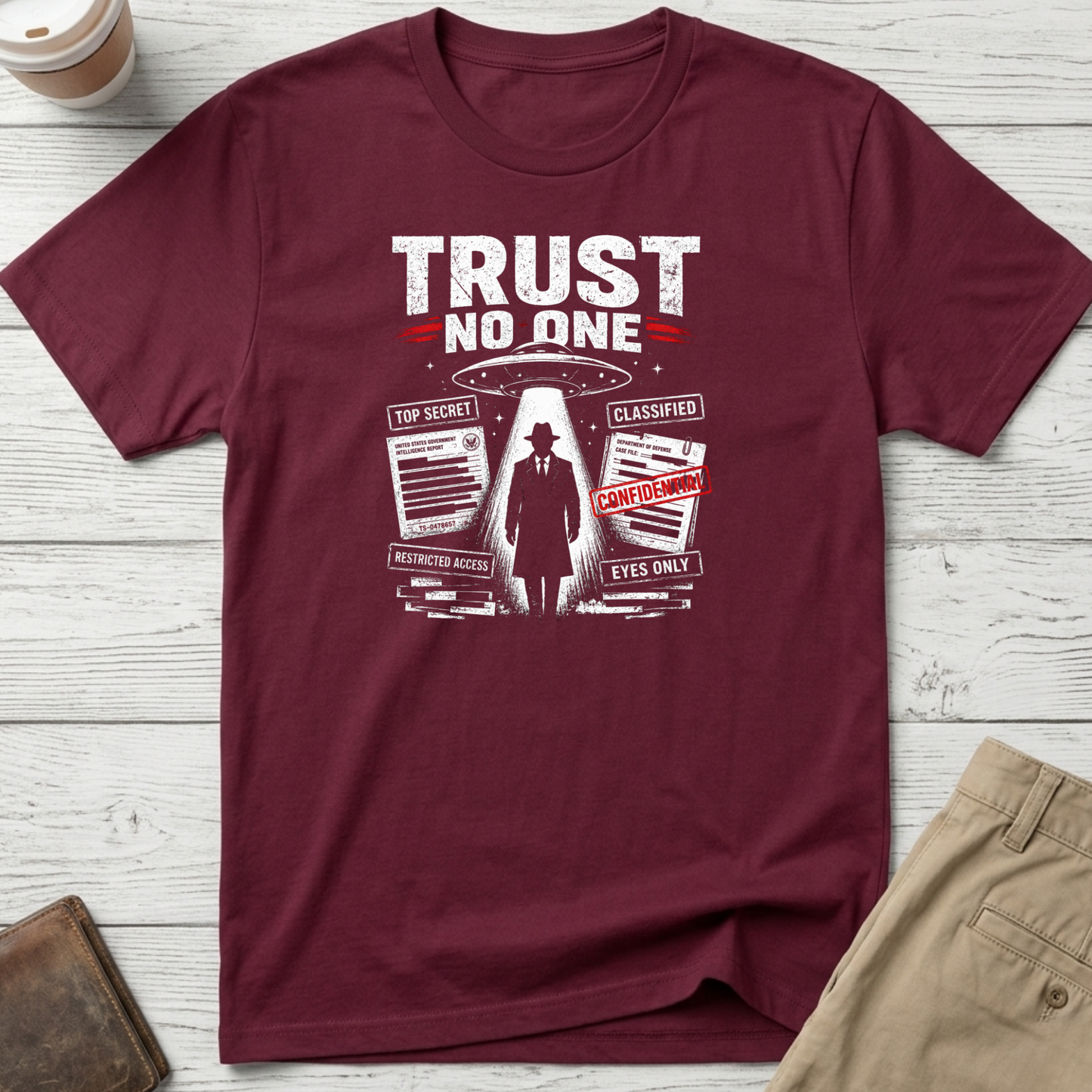Trust No One graphic t-shirt featuring UFO abduction artwork, classified documents and conspiracy-inspired design on maroon unisex tee.